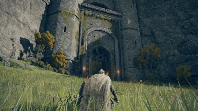 A cloaked figure in armor is kneeling in the grass near a castle.